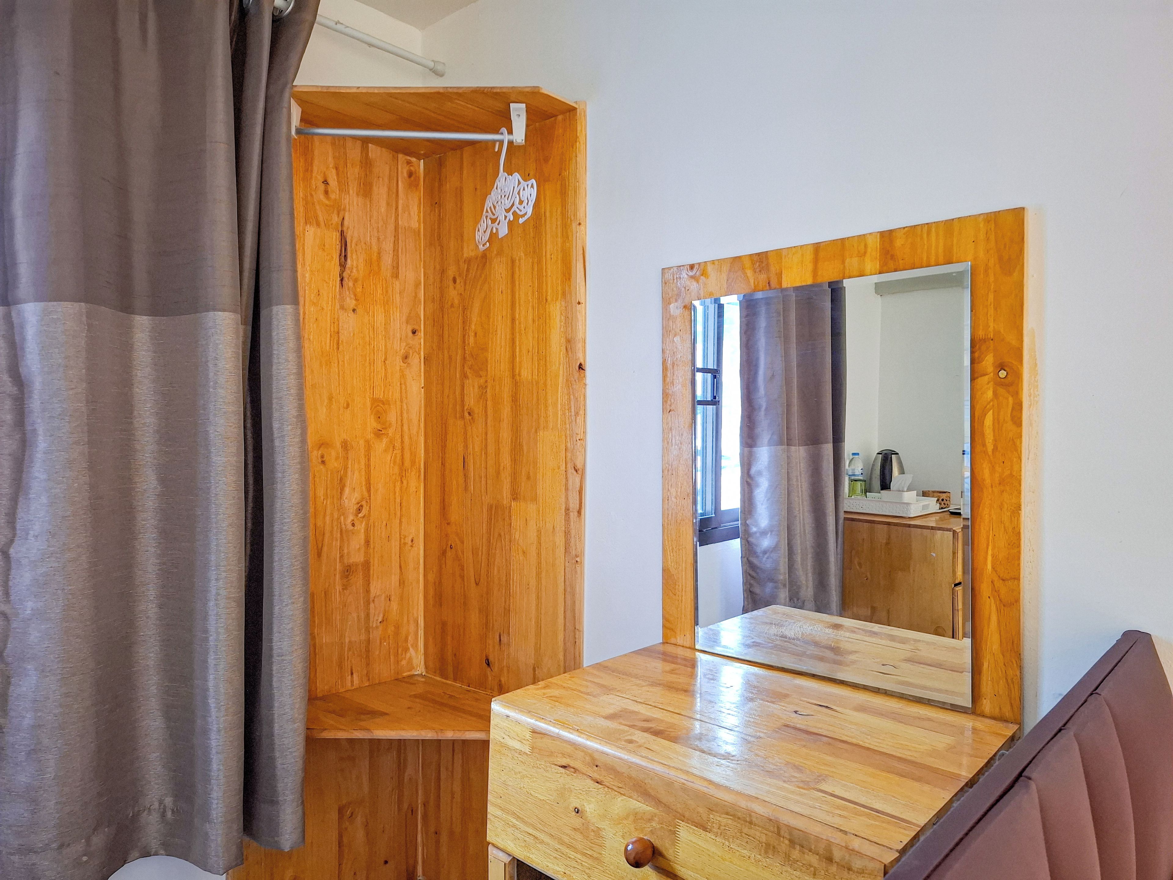 A wooden room with a mirror, a wooden bench, and a window.