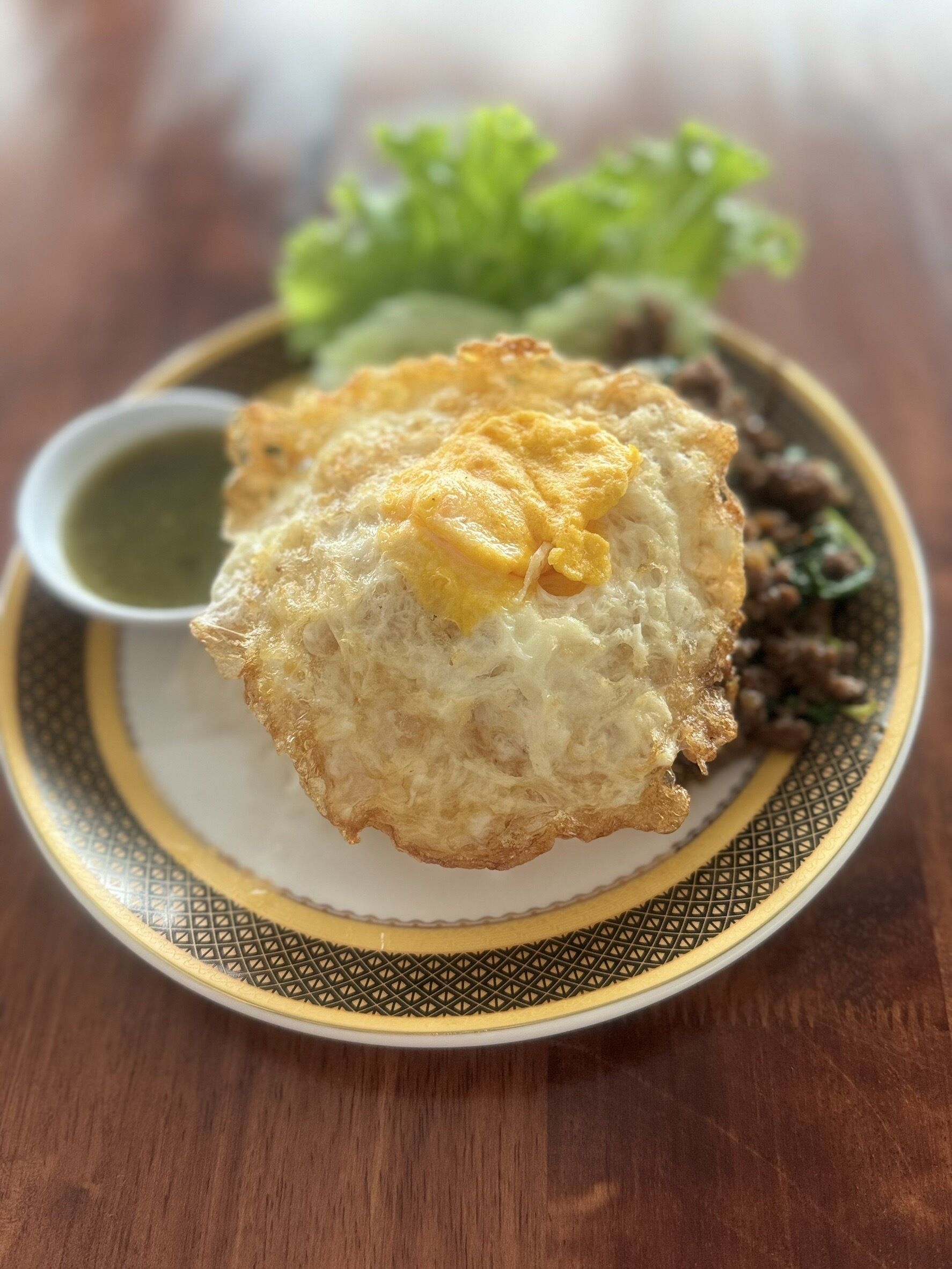 A plate with a fried egg, green sauce, and vegetables.