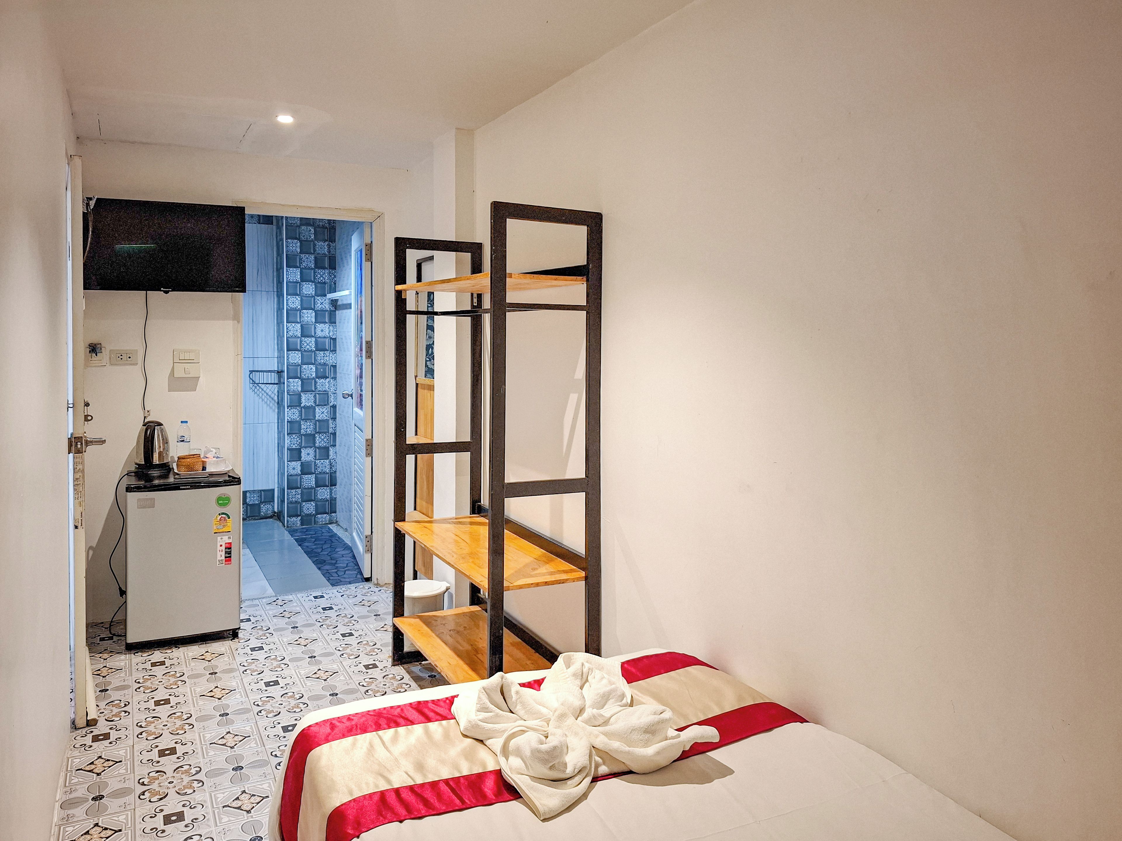 Ett kompakt hotellrum med en säng, ett litet kök och ett badrum som syns genom en öppen dörr.