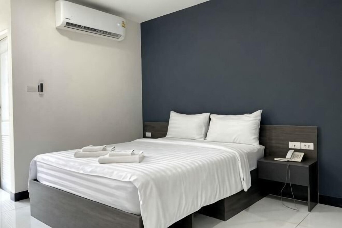 A modern hotel room with a bed, bedside table, and an air conditioning unit.