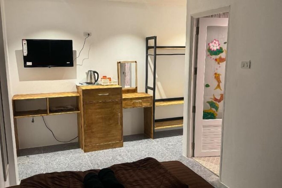 Une chambre à coucher avec un lit, un bureau en bois, une télévision et un lit superposé.