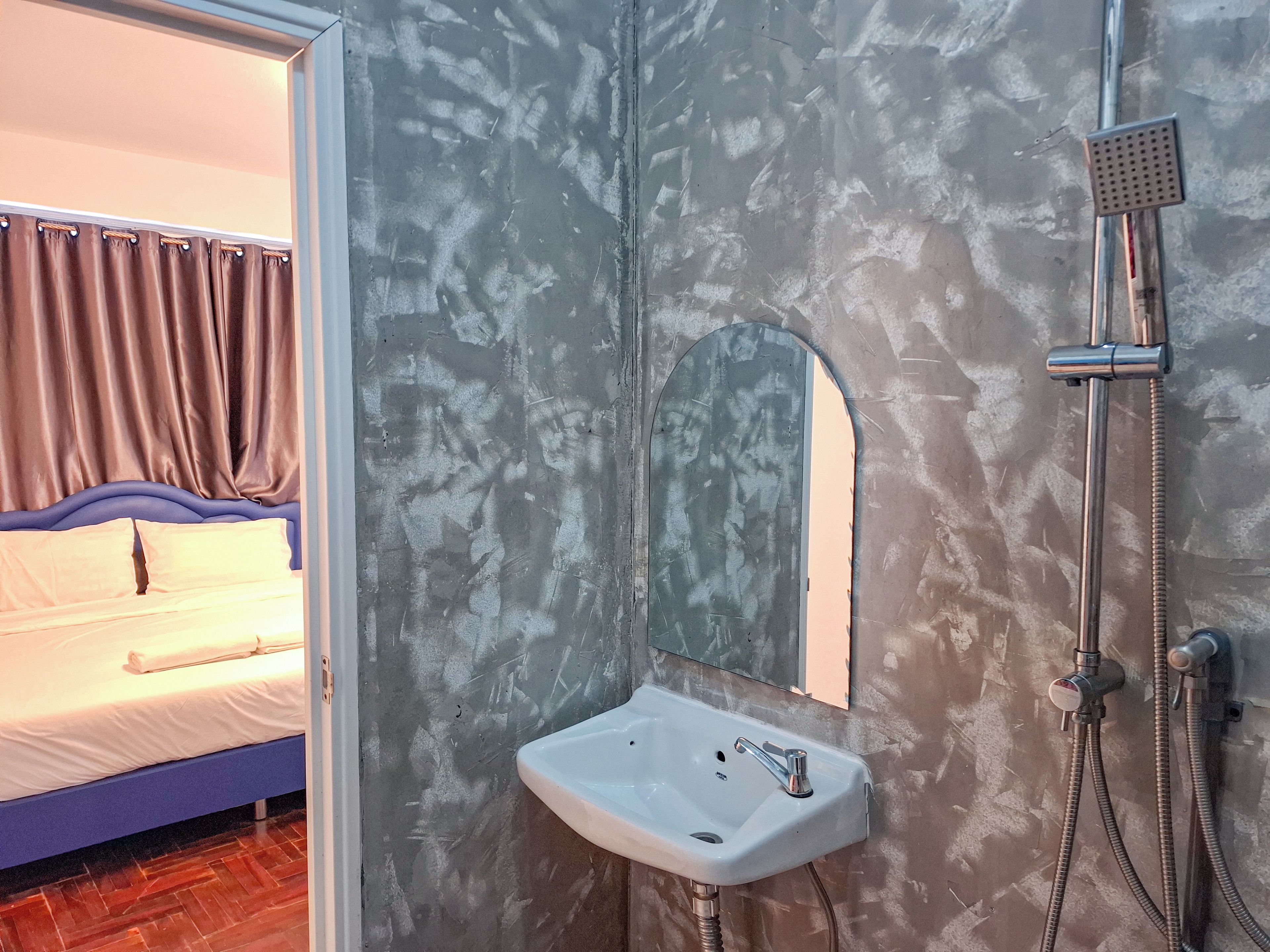 Un baño con lavamanos blanco, ducha y espejo.