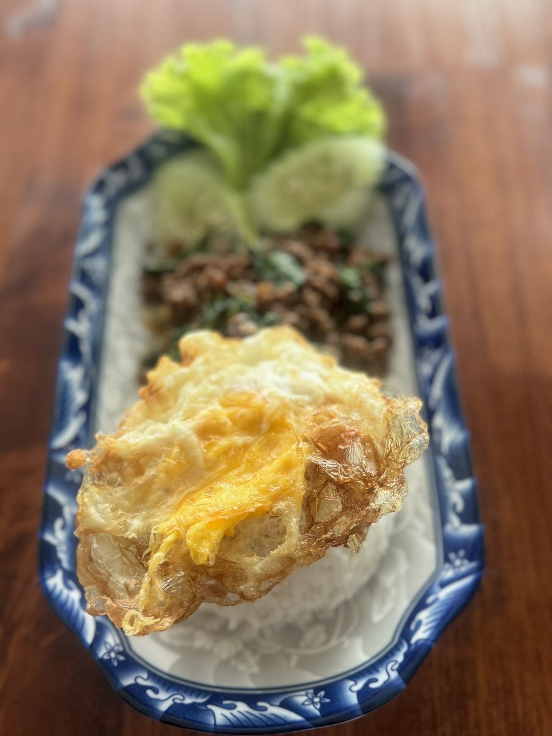 A plate of food with a fried egg, lettuce, and a meat dish.