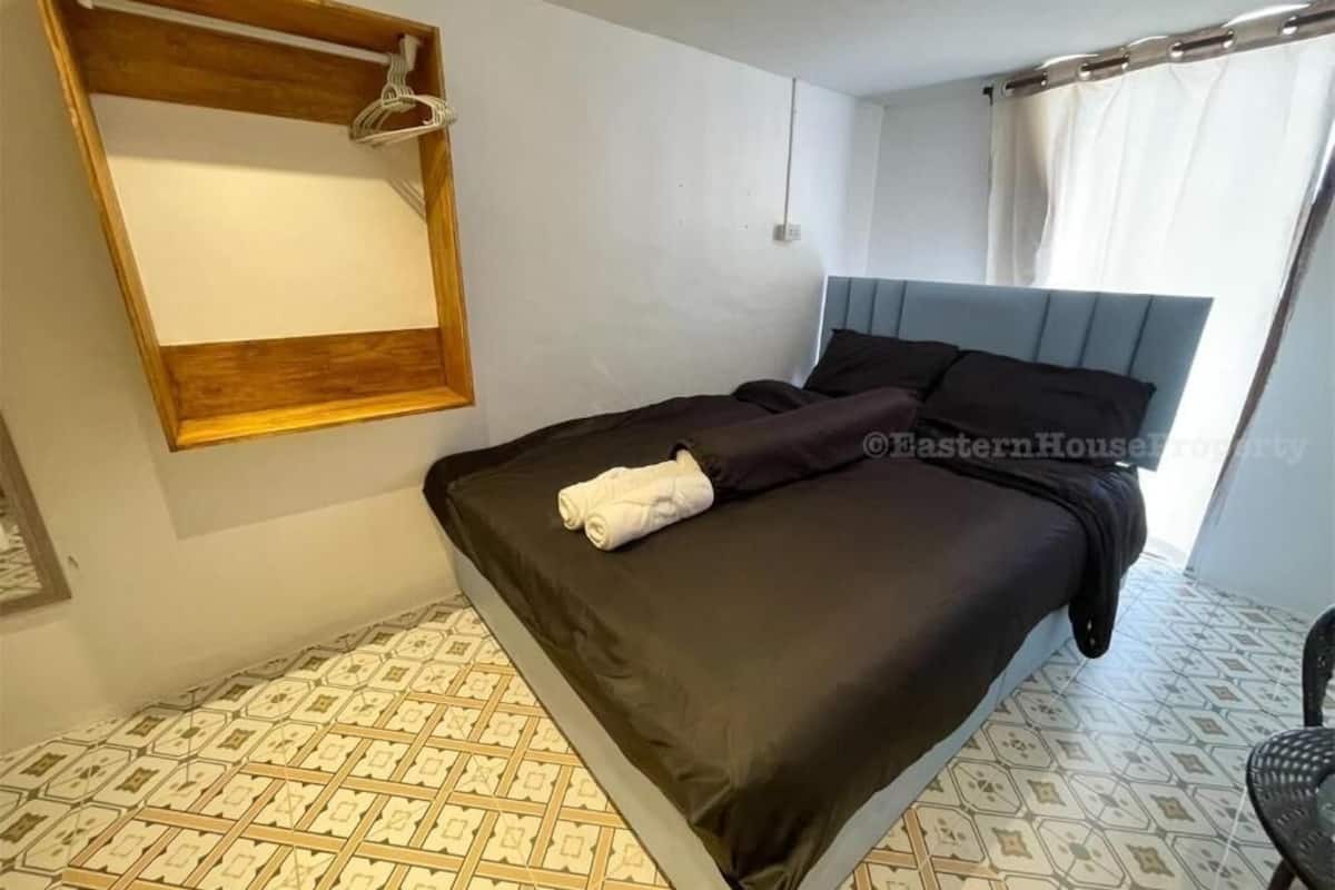 A bedroom with a bed, a wooden headboard, a hanging light fixture, and patterned floor tiles.