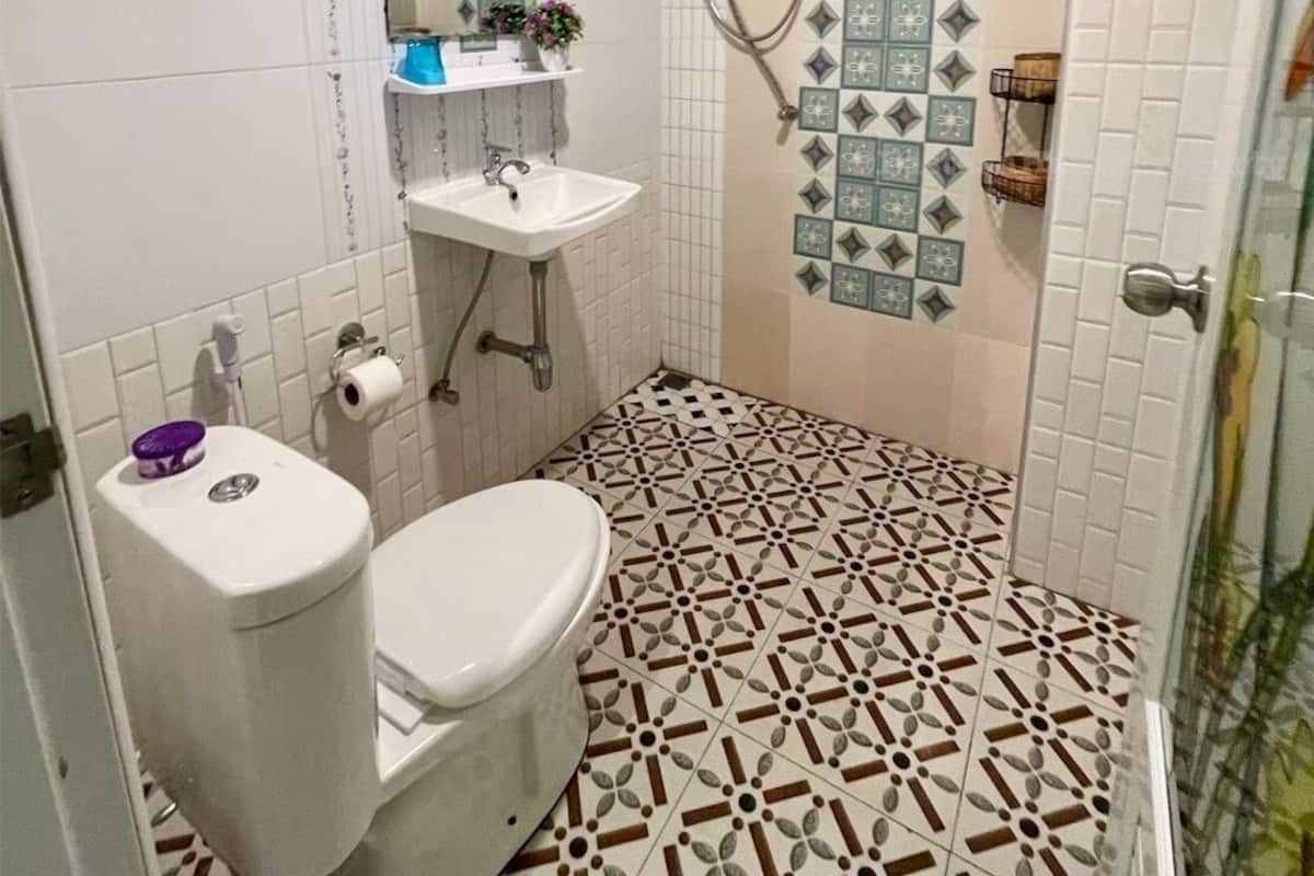 A bathroom with a toilet, sink, and shower. The floor has a geometric tile pattern.