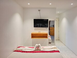 A modern bathroom with a wooden vanity, a mirror, and a flat-screen TV mounted on the wall. - YOK Guesthouse Jomtien (Pattaya)