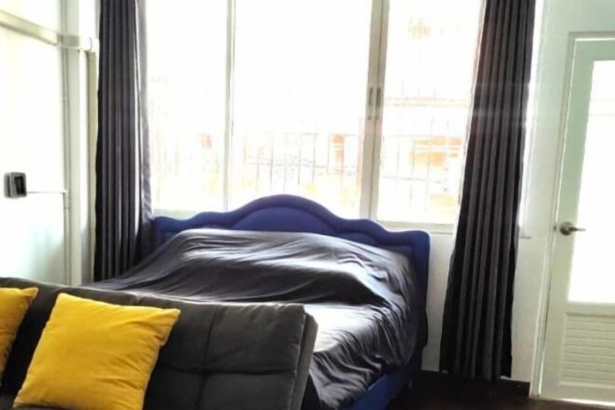 A room with a bed, a window with curtains, and a door.