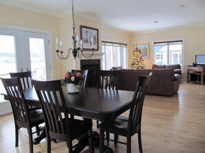 A dining area with a table and chairs, a chandelier, a fireplace, and a Christmas tree.