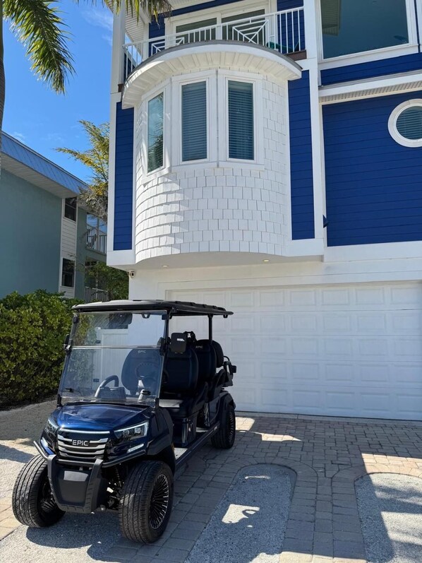 Ein modernes Gebäude mit blau-weißer Fassade, einem geschwungenen weißen Abschnitt und einem schwarzen Golfwagen davor.