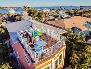 Ein mehrgeschossiges Gebäude mit einem Balkon, Sitzgelegenheiten im Freien und Blick auf das Meer.