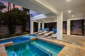 Ein moderner Poolbereich im Freien mit Liegestühlen und einer überdachten Terrasse.