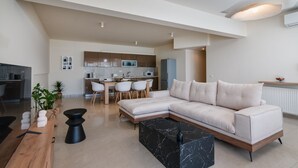 A modern living room with a sectional sofa, a dining table, and a kitchen in the background.