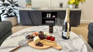 Une table en marbre avec une planche à fromages, des raisins, des fraises et une bouteille de champagne Chandon Brut.