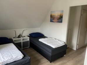 Cozy retreat with a single bed, nightstand, and a beautiful landscape painting.