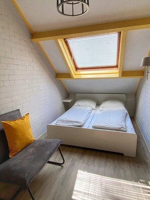 Cozy retreat with a single bed, skylight, and bench.