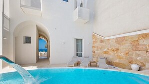 A pool area with a clear view of the sea, a white building with stone accents, and lounge chairs. - Palma Residence Salento (Melendugno)
