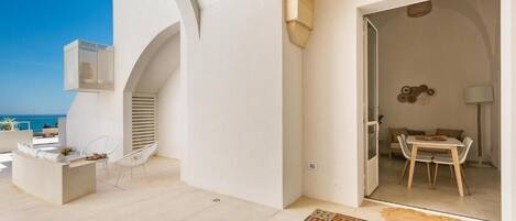 Un patio moderno al aire libre con zona de comedor, una silla blanca y una pequeña mesa.