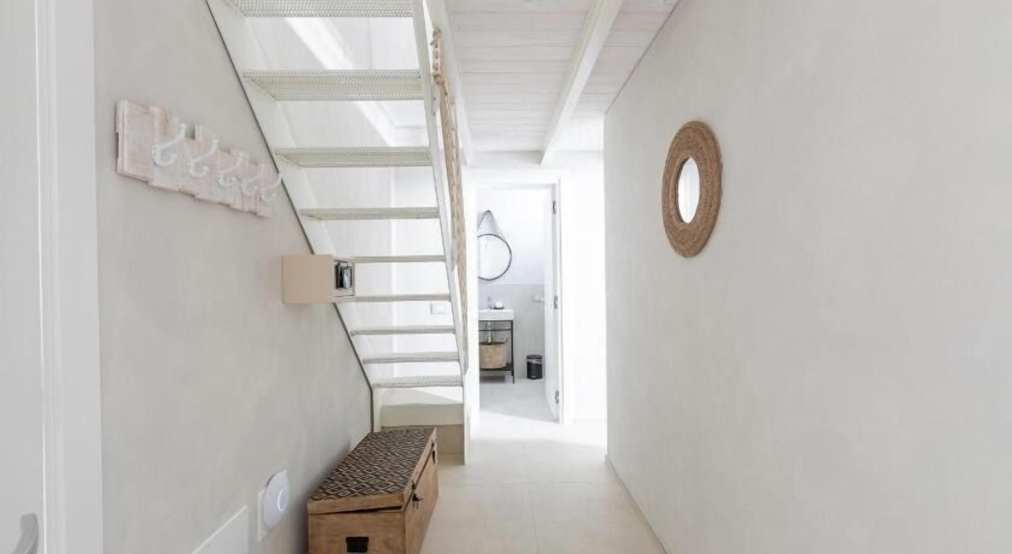 A hallway with a wooden bench, a staircase, and a circular wall decoration.