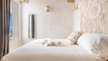 Un dormitorio con una cama grande, un adorno de macramé en la pared y una ventana con cortinas.