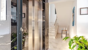 A modern interior with a marble wall, a staircase, and a potted plant. - Yamas Urban Living Platinum Key (Limassol)