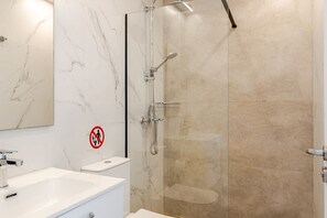 Un bagno con un lavabo in marmo, una doccia con porta in vetro e un cartello di divieto di accesso.