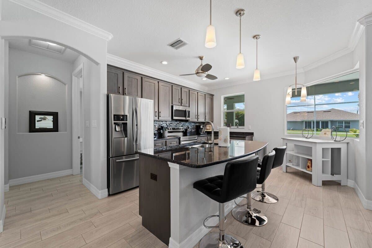 A modern kitchen with stainless steel appliances, a central island with bar stools, and pendant lighting.