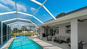 A covered swimming pool with a glass ceiling, outdoor furniture, and a view of the neighborhood. - Sun-Soaked & Tranquil Getaway  Relaxing Pool Area (Rotonda West)