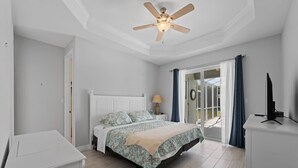 A bedroom with a bed, a nightstand, a ceiling fan, a TV, and a view through a glass door. - Sun-Soaked & Tranquil Getaway  Relaxing Pool Area (Rotonda West)