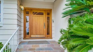 A wooden front door with a glass panel, a stone staircase leading up to it, and a white railing on the left.