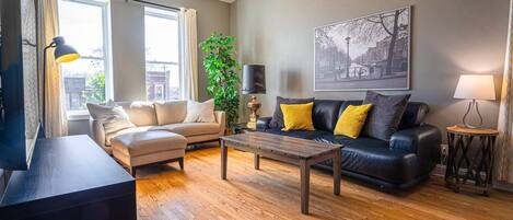 A living room with a sofa, a coffee table, a TV, and a ceiling fan.