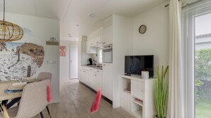 Una cocina moderna con armarios blancos, horno empotrado y televisor de pantalla plana.