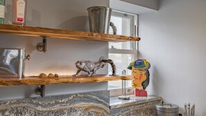 Een keuken met marmeren aanrecht, een koffieapparaat en een decoratief kikkerbeeldje.