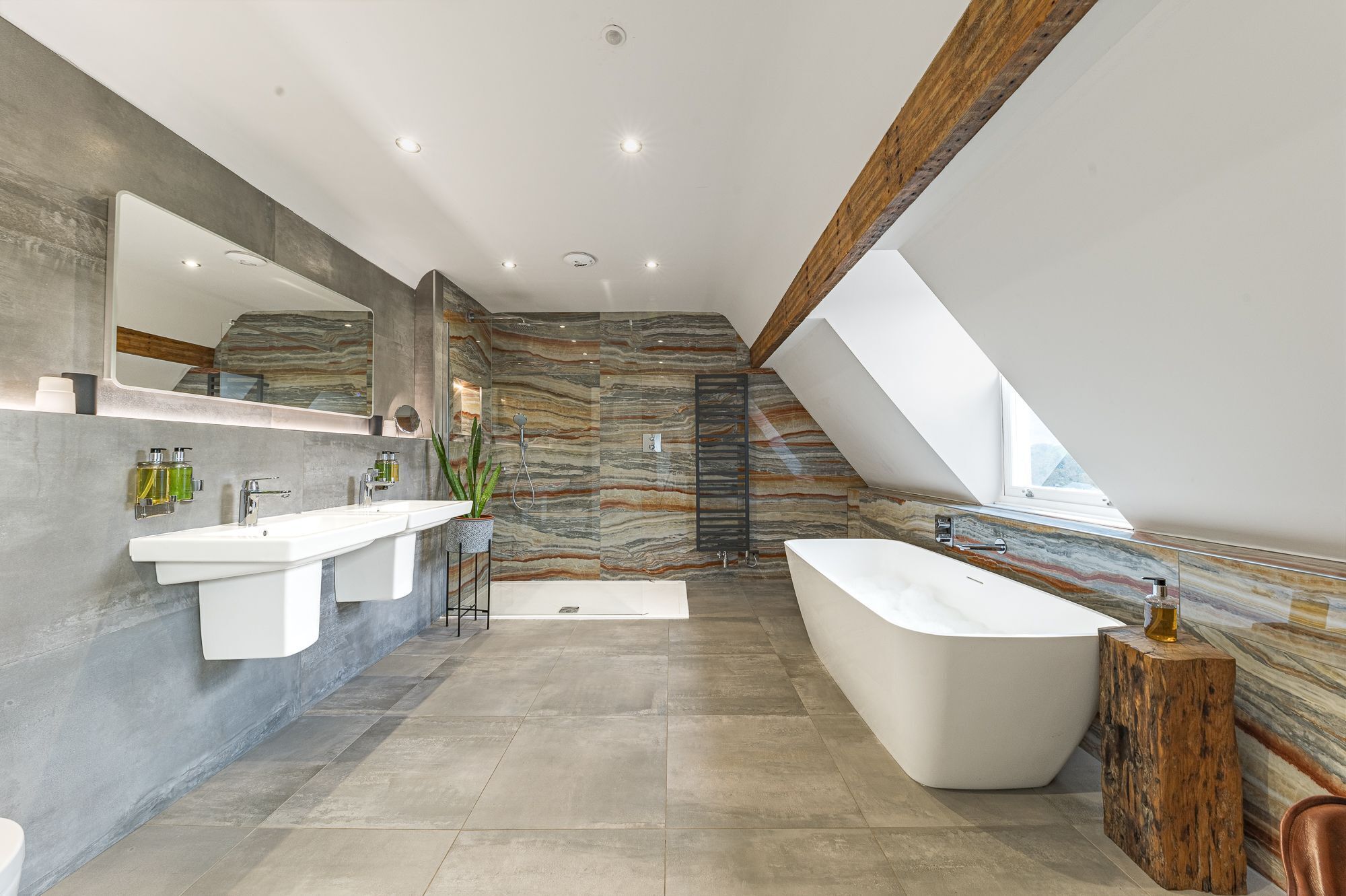 Een moderne badkamer met een vrijstaand bad, een grote spiegel en een douche.