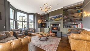 Een moderne woonkamer met leren banken, een open haard, boekenkasten en grote ramen.
