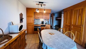 A compact kitchen with wooden cabinets, a dining table with a heart-patterned tablecloth, and a built-in oven. - Cozy T2 Apartment with Terrace, 5 pers, Les Saisies (Les Saisies)