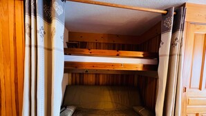 A bunk bed room with wooden beams, a curtain, and a wooden door. - Cozy T2 Apartment with Terrace, 5 pers, Les Saisies (Les Saisies)