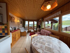 A cozy cabin interior with wooden walls, a dining area, and a view of the outdoors.