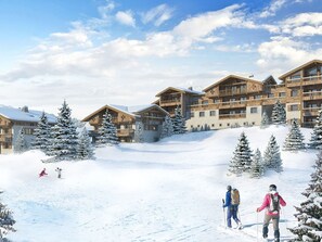 Ein Skigebiet mit mehreren Holzhäusern, schneebedeckten Bäumen und Skifahrern auf den Pisten.