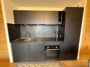 A compact kitchen with a built-in oven, a sink, and a stove.