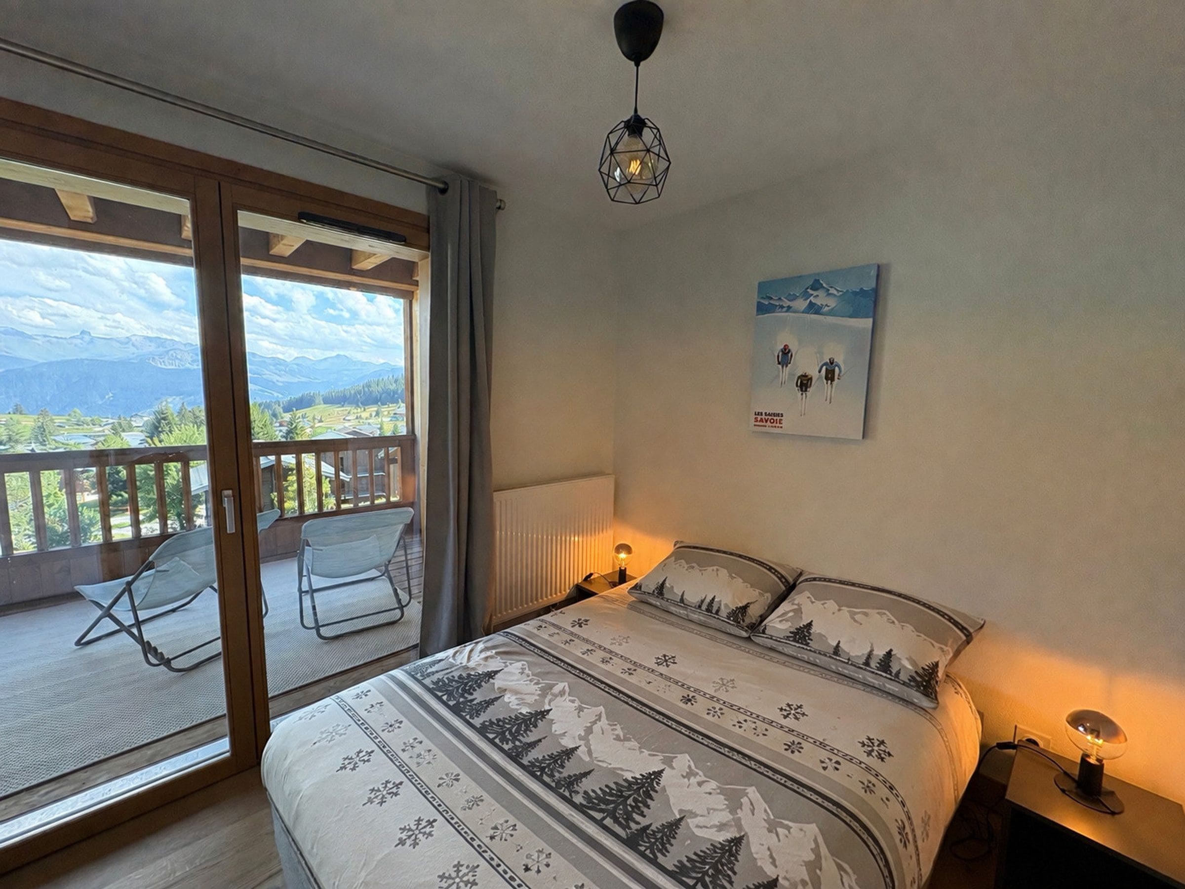 A bedroom with a bed, a chair, a nightstand, a lamp, a poster, and a view of the outdoors.