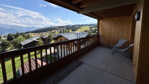 Un balcon en bois offrant une vue sur un village et des montagnes.