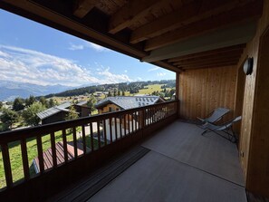 A wooden balcony with a view of a village and mountains. - New apartment 50m², 2 bedrooms, WIFI, covered parking (Les Saisies)