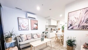 A modern living room with a sofa, coffee table, and kitchen in the background. - Centrally Located Luxury Apartment in Canberra (Canberra)