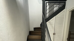 A staircase with wooden steps and a metal railing, leading to a room with a white door and a window.