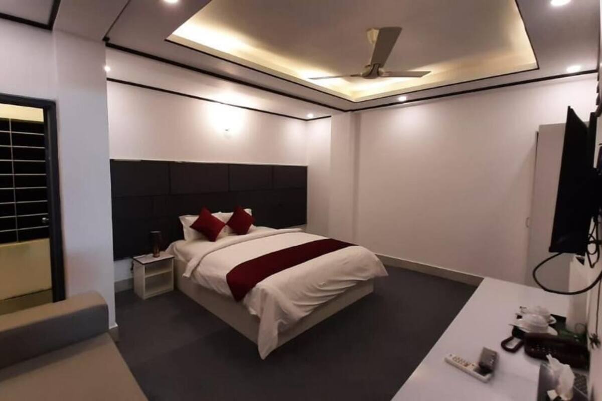 A modern bedroom with a bed, bedside tables, a ceiling fan, and a TV mounted on the wall.