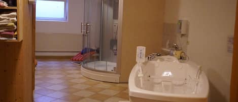 A bathroom with a white bathtub, a glass-enclosed shower, and a tiled floor.