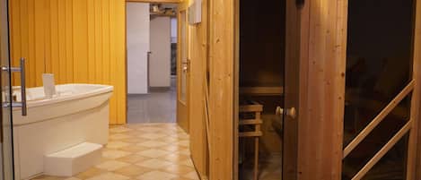 A bathroom with a white bathtub, wooden cabinets, and a checkered floor.