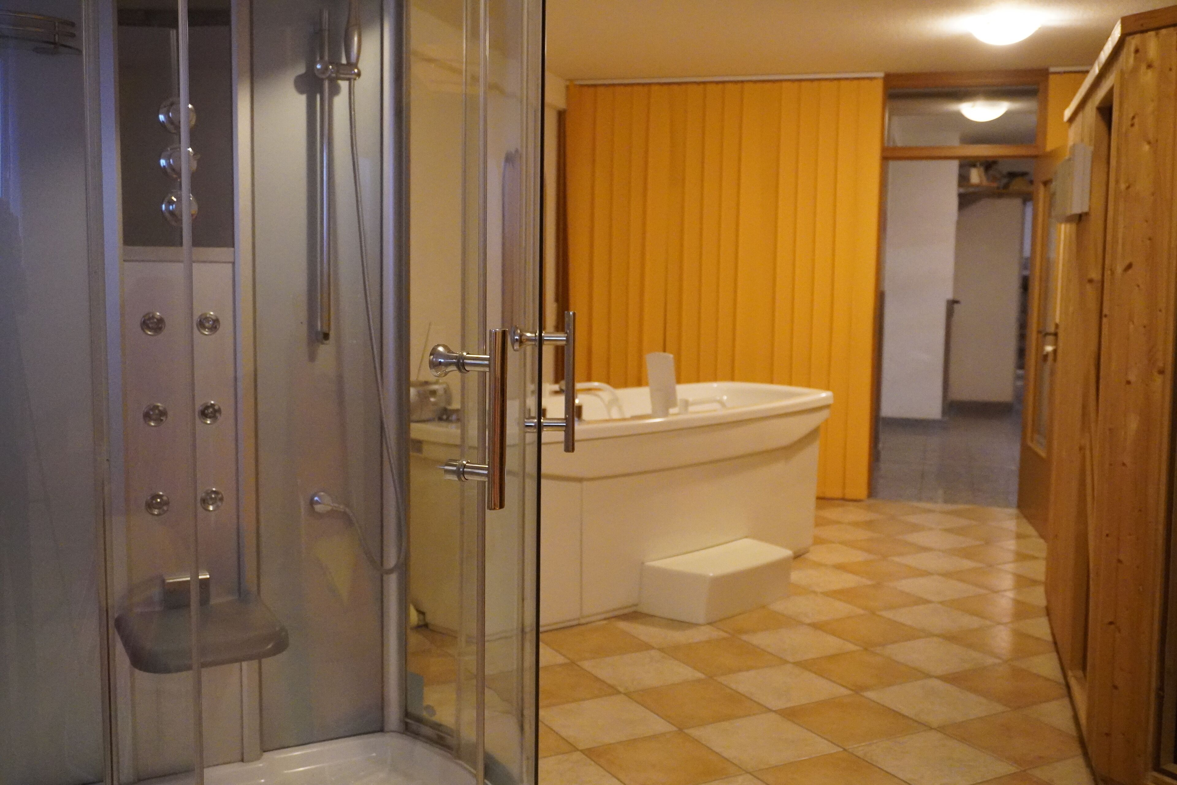 Un baño con cabina de ducha de vidrio, una bañera blanca y suelo a cuadros.