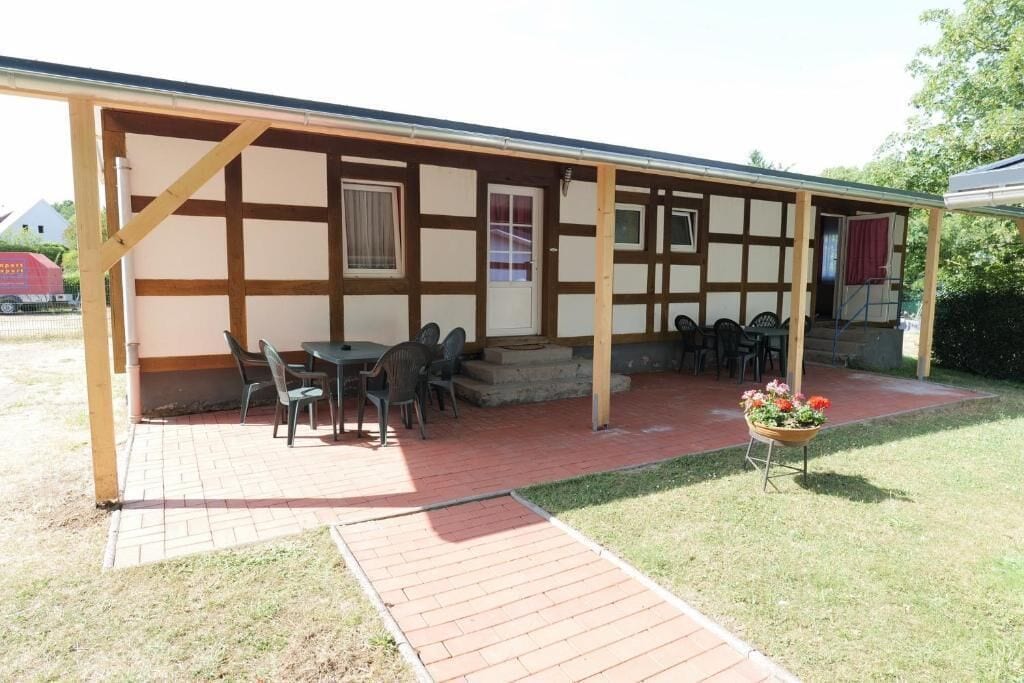 A covered outdoor seating area with a table and chairs, a small entrance, and a flower pot.