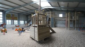A large indoor play area with various climbing structures and a slide.